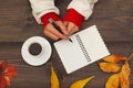 Hands of woman with a pen and notebook at a wooden table with cup of espresso and autumn leaves Royalty Free Stock Photo