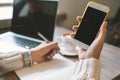 Hands of woman with pen and notepad, holding smartphone with coffee