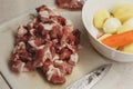 Hands of a woman in process of slicing raw meat on a plastic cutting board