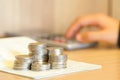 Hands of woman pushing on calculator with account book and coins