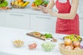 Hands of woman with red apron use mobile phone take photo of plate of slicing fish in kitchen with different type of ingredients