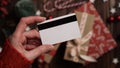 Hands of a woman in a red sweater with a credit card on a background of gift boxes, selective focus, close-up. Christmas and New Royalty Free Stock Photo