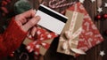 Hands of a woman in a red sweater with a credit card on a background of gift boxes, selective focus, close-up. Christmas and New Royalty Free Stock Photo