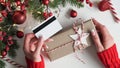 Hands of woman in red sweater holding credit card and gift box on white background close-up,top view,flat lay,copy space.Christmas Royalty Free Stock Photo