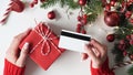 Hands of woman in red sweater holding credit card and gift box on white background close-up,top view,flat lay,copy space.Christmas Royalty Free Stock Photo