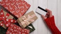 Hands of woman in red sweater holding credit card and gift box on white background close-up,top view,flat lay,copy space.Christmas Royalty Free Stock Photo