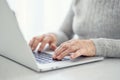 Hands of a woman senior work at a laptop close-up using modern technology in everyday life. Royalty Free Stock Photo