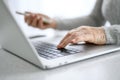 Hands of a woman senior work at a laptop with a phone using modern technology in everyday life Royalty Free Stock Photo