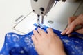 Hands of a woman sewing blue fabric