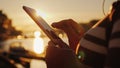 Hands of a woman with a smartphone on the background of a pier with yachts at sunset