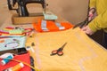 Hands woman Tailor working cutting a roll of fabric on which she has marked out the pattern of the garment she is making with tail