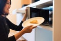 Hands woman using microwave oven with bread in home kitchen Royalty Free Stock Photo