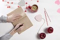 Hands of a woman who is going to draw by a pencil in a notebook. On the table there is a cup of tea with lemon, apples and paper h