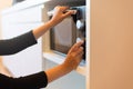 Hands woman using microwave oven in home kitchen