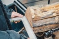 The hands of a woodworker are measuring a log with a metal ruler. Woodworking, wood products, work, employment