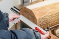 The hands of a woodworker are measuring a log with a metal ruler. Woodworking, wood products, work, employment