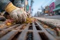 Hands in work gloves removing weeds and debris from a street gutter drain Royalty Free Stock Photo