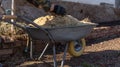 Hands in work gloves throw sawdust on a one wheeled cart