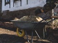 Hands in work gloves throw sawdust on a one wheeled cart