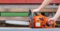 Hands of a worker with a chainsaw on a wood background. Concept worker lumberjack. Adjustment and maintenance of