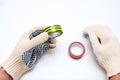 Hands of a worker, electrician in protective gloves holding rolls of electrical isonation duct tape, red and yellow