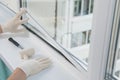The hands of the worker, install a double-glazed window in the plastic frame of the window, fixing it with a rubber mallet Royalty Free Stock Photo