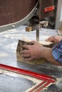 Hands of a worker sawing firewood with an industrial bandsaw