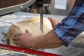 Hands of a worker sawing firewood with an industrial bandsaw