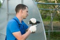 The hands of the worker twist the polycarbonate sheet with a screwdriver for installation on the greenhouse