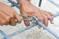 Hands of worker use pincers for knitting metal rod