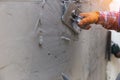 The hands of a worker who are plastering up close are wearing orange rubber gloves to prevent the cement from biting their hands,