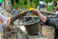 Hands of workers help to carrying the dirty bucket of mixed cement at the construction site. Teamwork concept