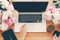 Hands working on stylish laptop with empty screen, coffee cup, notebook,phone, pink and white peonies on wooden table flat lay Royalty Free Stock Photo