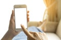 The hands of a working woman who holds a smart phone by her lying on the couch.