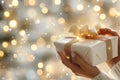 Hands wrapping a ribbon on a gift box in front of a christmas tree with warm lights Royalty Free Stock Photo