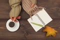 Hands of writer with a cup of coffee and scarf at wooden table with notebook and pen and autumn leaves Royalty Free Stock Photo