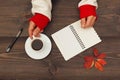 Hands of writer hold a cup of coffee at a wooden table with notebook and pen and autumn leaves Royalty Free Stock Photo