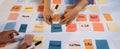 Colorful Sticky Notes Display on Table for Team Brainstorming Session with Hands Writing Ideas, Strategies, and Plans Royalty Free Stock Photo