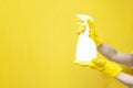 hands in yellow cleaning gloves hold detergent in bottle, empty cleaning spray in the hands of person