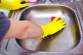 Hands in yellow gloves clean sink with sponge and a special cleaning agent, detergent spray. Hygiene in the kitchen, cleaning the Royalty Free Stock Photo