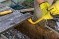 hands in gloves prying boards with crowbar