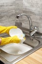 Hands in yellow gloves washing bowl against kitchen sink Royalty Free Stock Photo