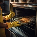 hands in yellow household gloves clean the oven