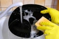 Hands in yellow protective rubber gloves washing dishes in the kitchen under running water. Close-up Royalty Free Stock Photo