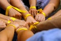 Hands with yellow ribbons together.
