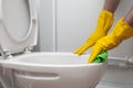 Hands in yellow rubber gloves cleaning toilet with green cloth Royalty Free Stock Photo