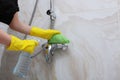 Hands in yellow rubber gloves wash the faucet in the shower stall. Unrecognizable photo.Cleaning at the hotel or at home
