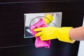 Hands with yellow rubber protective gloves cleaning toilet flush button Royalty Free Stock Photo