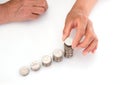 Hands with yellow skin looking down on white background are stacking dollar coins