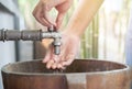 Hands of a Young Asian woman open and touching running water from a Asian retro style water faucet